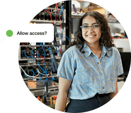 Smiling woman standing in front of a networking rack of data equipment.